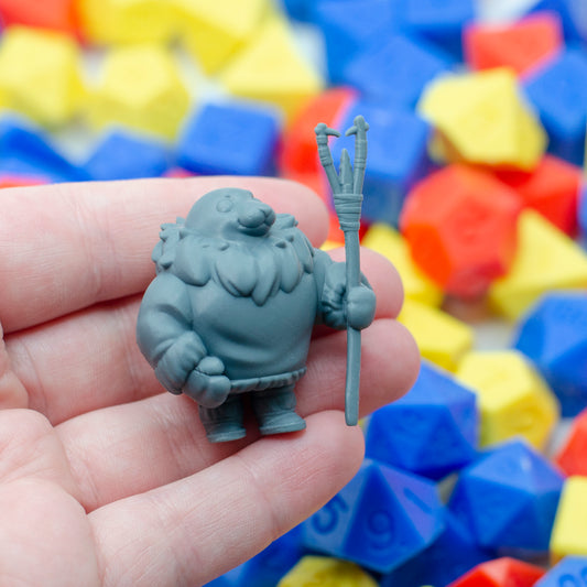 3d resin miniature of a parent seal fisher, holding the kakivak style spear. It's held in a hand, showing its small scale.