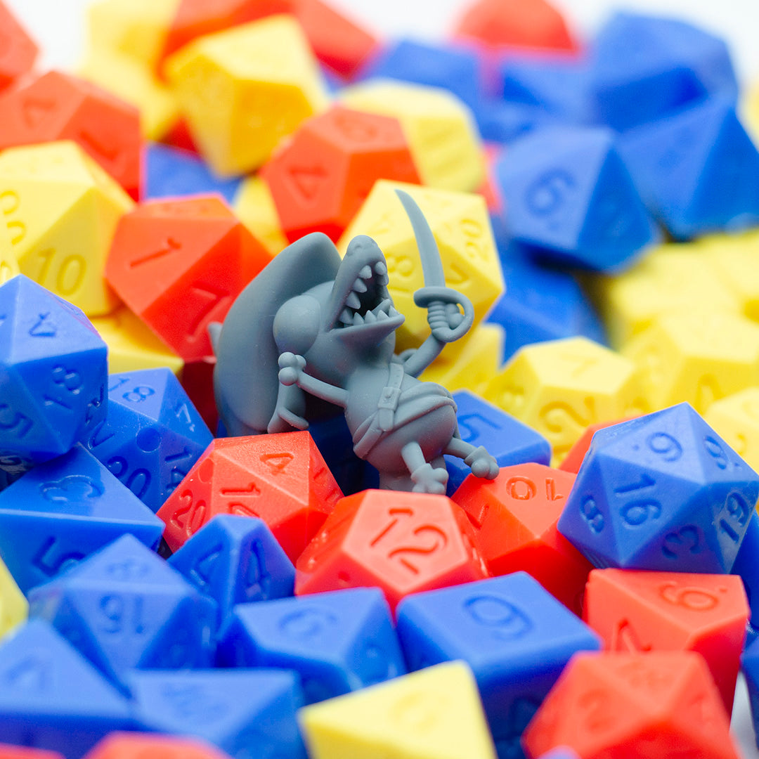 3D printed grey mini of a kobold swashbuckler, looking happy in a pile of dice.