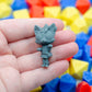Gray 3d printed TTRPG figurine of a cat girl wearing a school uniform and hoodie held in a hand with colorful dice in the background