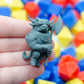 Gray 3d printed miniature figurine of a highland cattle minotaur with an axe, held in a hand against a colorful dice background