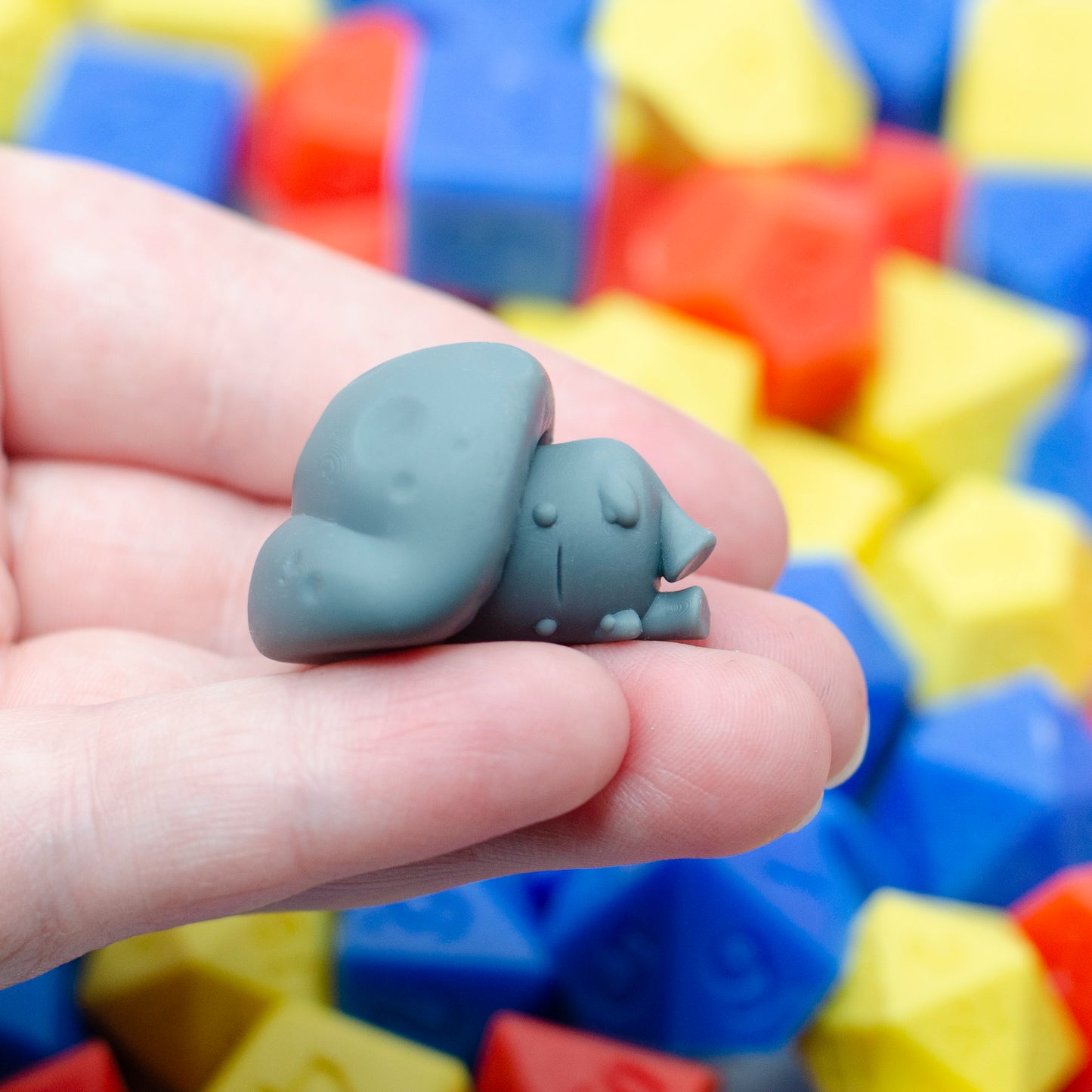 A 3d printed mushroom guy with little stumpy legs. It's laying on its side with a blank expression.