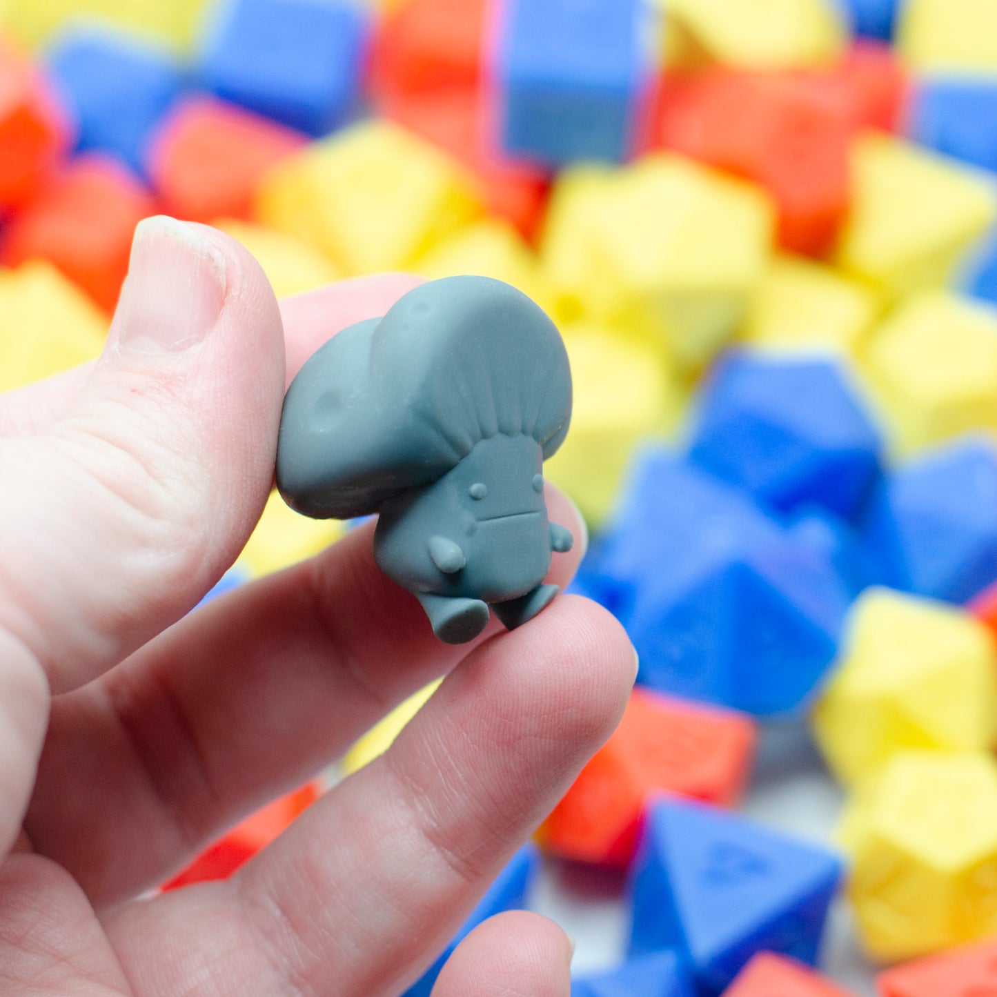 The bottom view of a 3d printed mushroom guy laying on its face, showing its smushed expression.