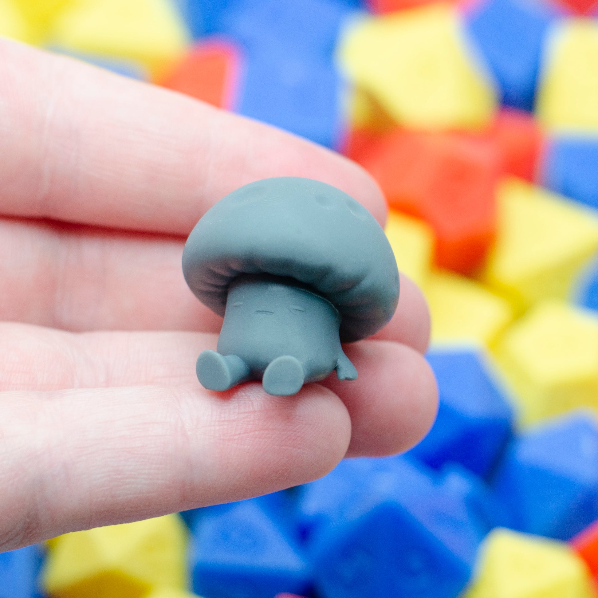 A mushroom guy leaning back with an exhausted expression, held in a hand for scale.