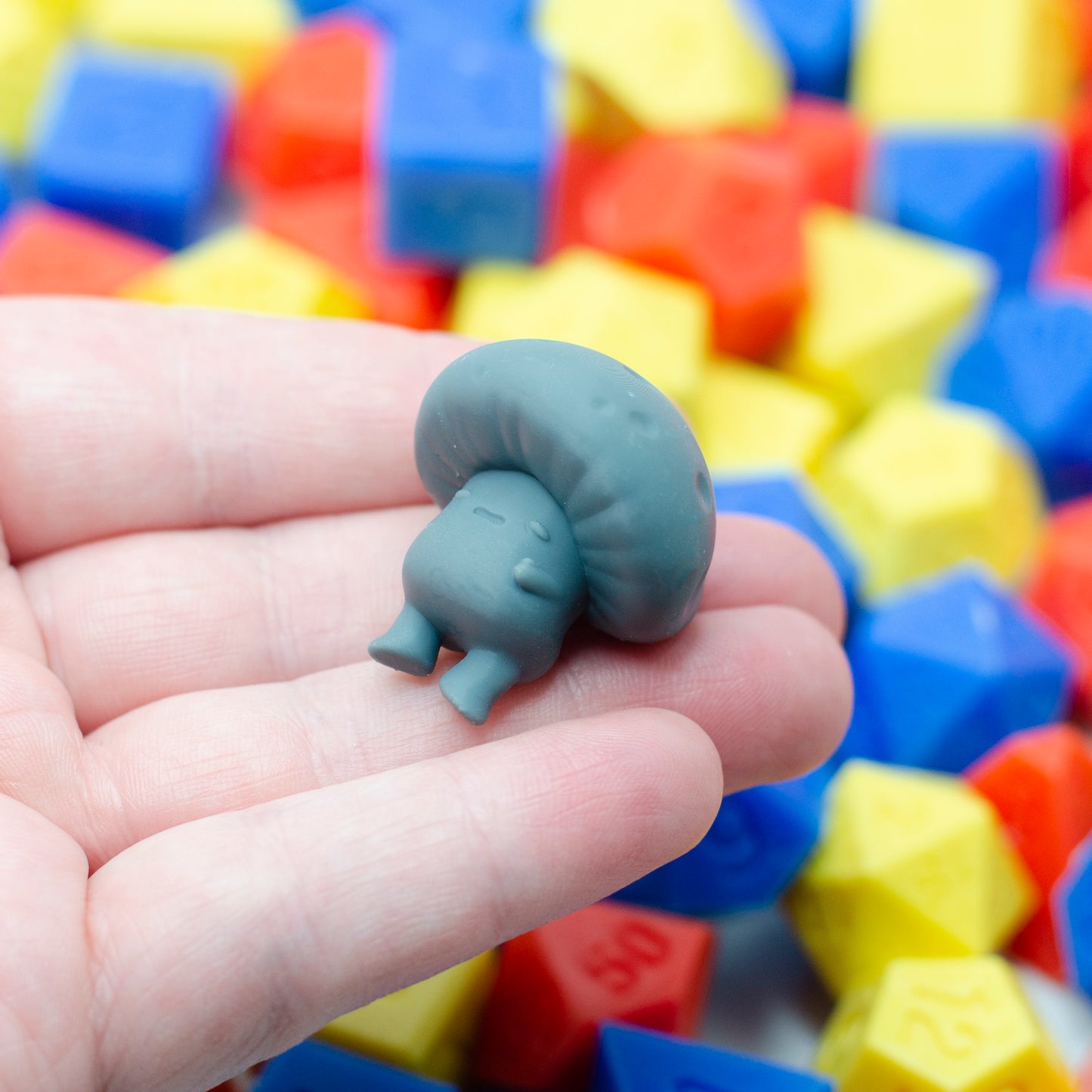 A 3d printed mushroom guy laying on its back, holding its tummy and looking tired.