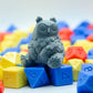 Resin print of a cartoony owlbear sitting on colorful dice.