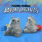 Two gray owlbear TTRPG miniatures with 'Found Family Adventurecrafts' text on a blue background