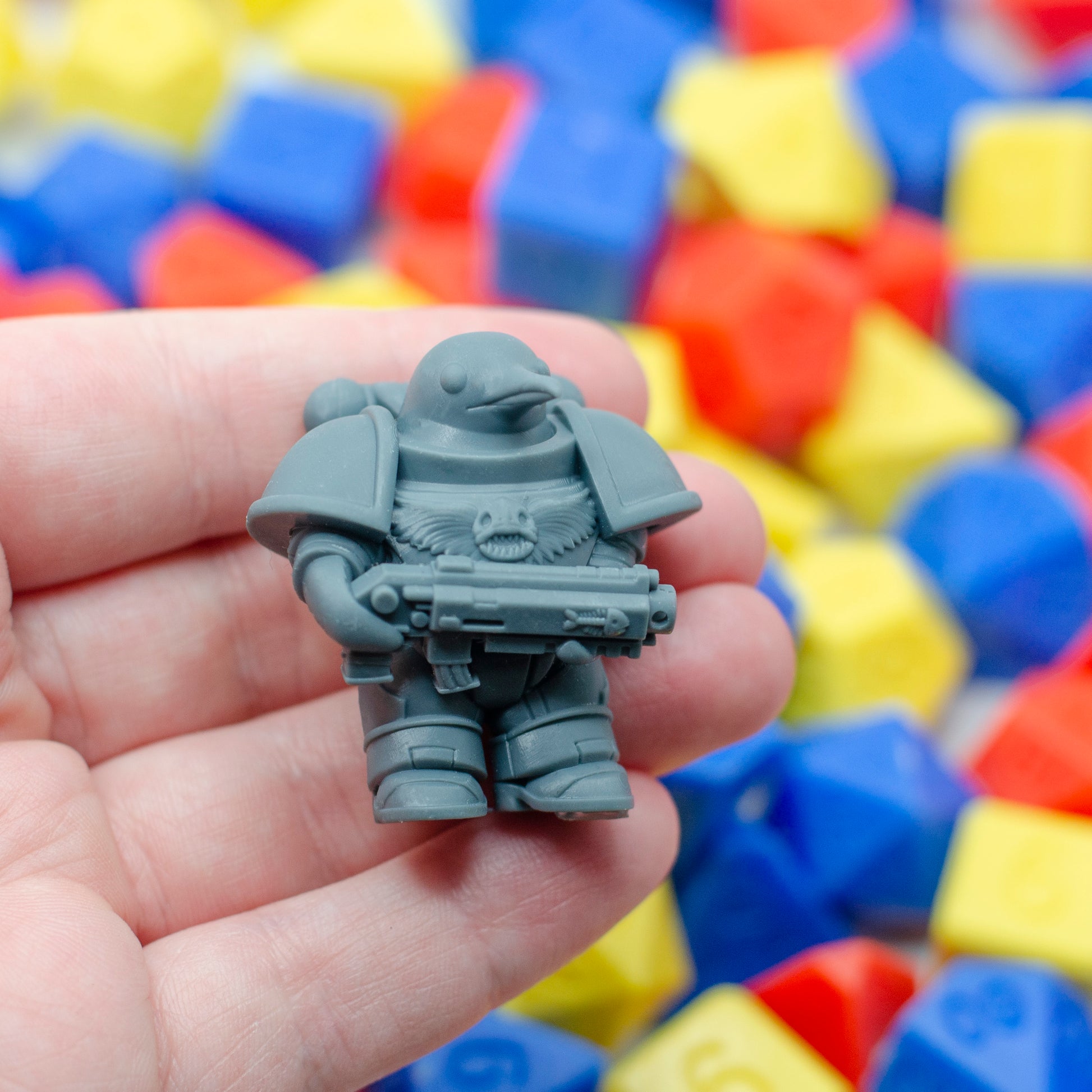 3d resin print of a miniature character: a classic warhammer style space marine mini - except that it's a stumpy, cute penguin! The emblems on the breast plate and gun are fish bones.