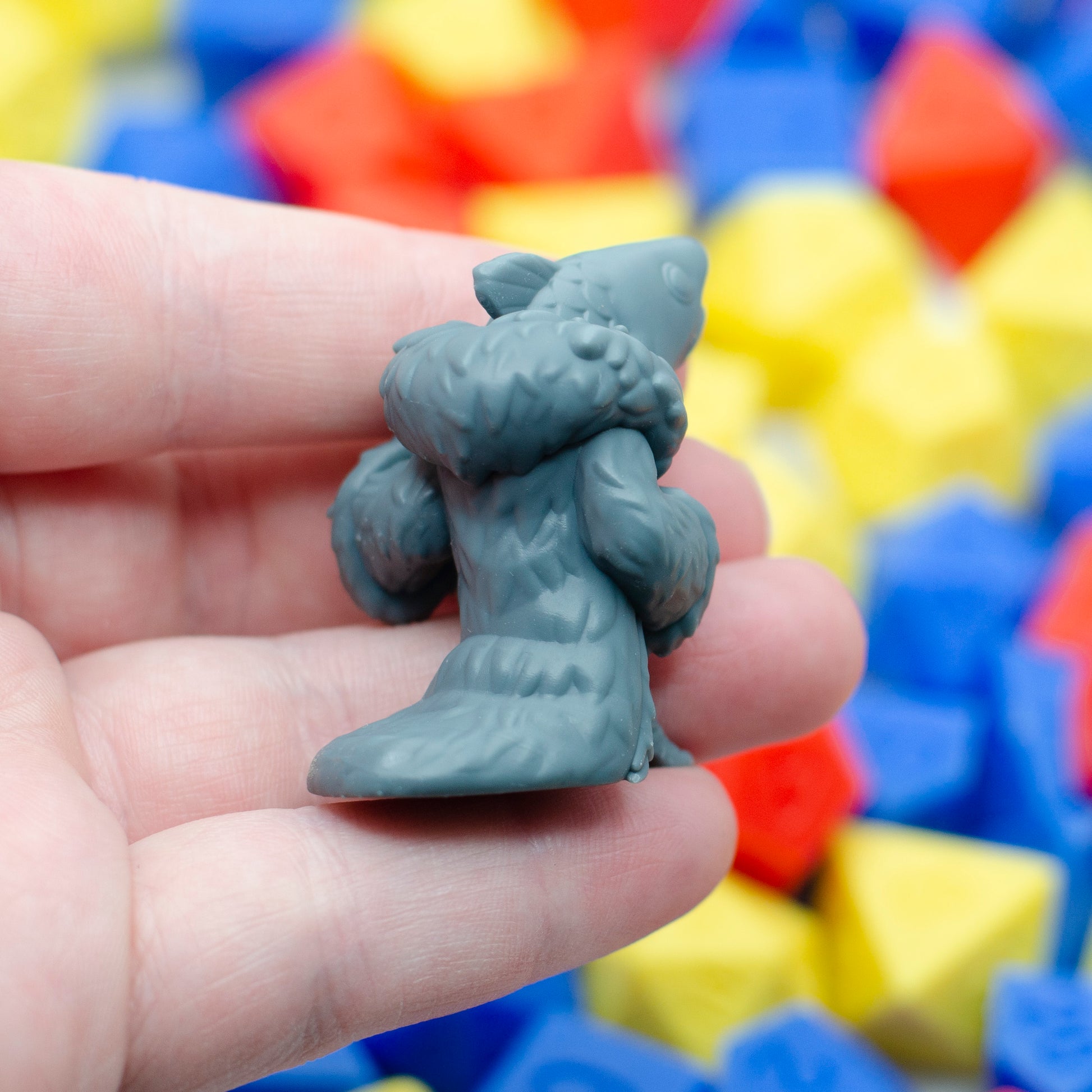 A reverse mermaid mini figurine 3d printed in resin, held in a hand. Viewed from the back, it shows the detail of the fur cloak.