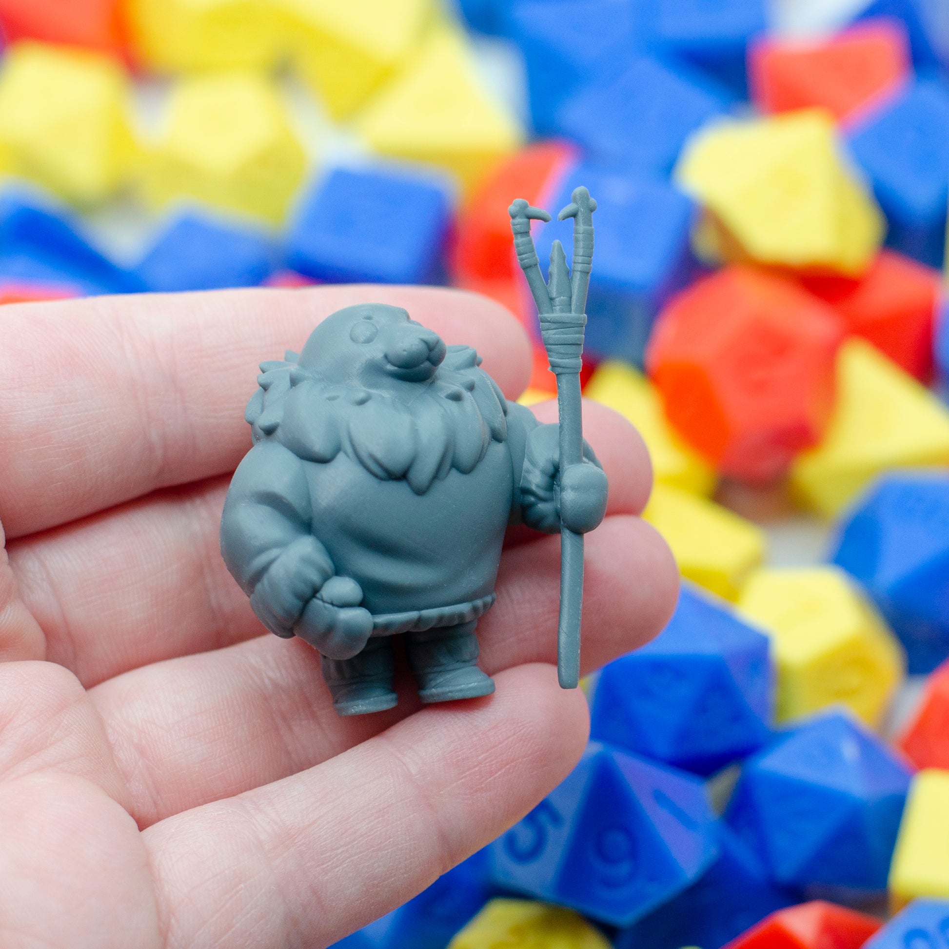 3d resin miniature of a parent seal fisher, holding the kakivak style spear. It's held in a hand, showing its small scale.