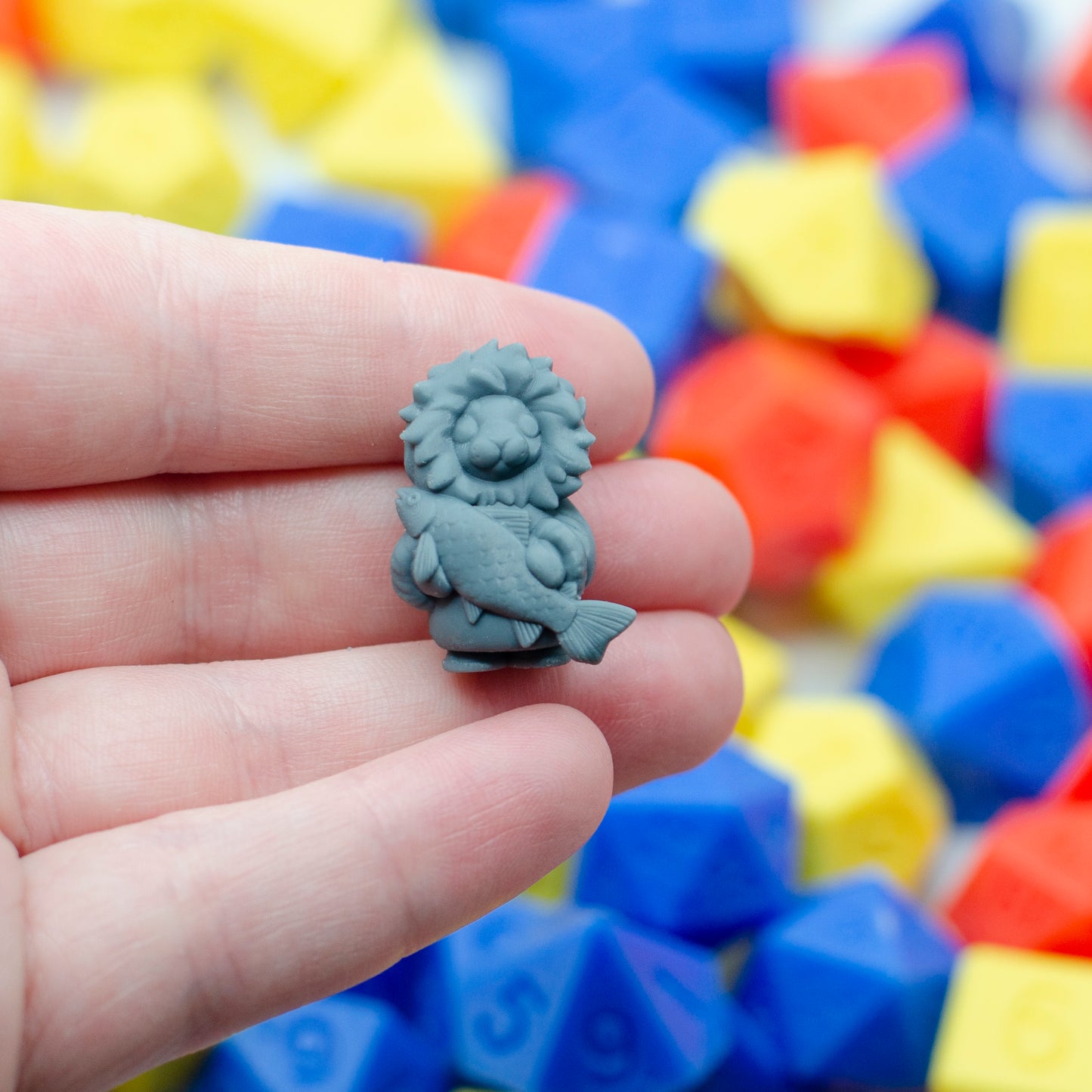 The 3d printed miniature of a little baby seal, all cuddled up in mitts and a parka holding the fresh fish catch. It's held in a hand, showing its tiny scale.